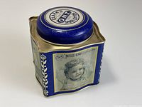 Front side of the tin with illustration of a smiling child with a bow in her hair and Clark's Mile-End Spool Cotton branding.