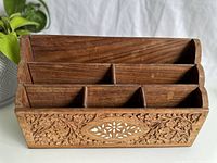 Front view of vintage wooden organizer showing three-tier stepped compartments and floral carving with white inlay detail.