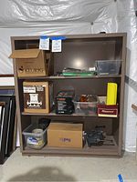 Full view of metal shelving unit with boxes and containers holding router, nails, clamps, and cutlery sharpener.