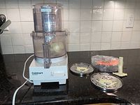 Cuisinart Pro Classic food processor on kitchen counter with two metal slicing/shredding discs and one blade attachment arranged alongside it.