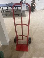 Front view of the red metal handtruck standing upright on carpet.