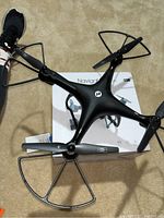 Holy Stone Navigator HS100 drone with protective propeller guards shown on top of its white box with product details visible
