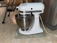 Side view of white KitchenAid Classic stand mixer with stainless steel mixing bowl attached and power cord visible.
