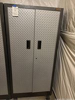 Front view of closed Gladiator metal cabinet showing diamond-plate doors and recessed handles
