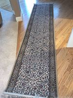 Full length view of the floral runner rug laid out on a hardwood floor showing the intricate design and overall condition.