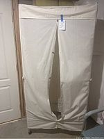 Front view of large fabric covered garment rack with zippered cover closed and slightly torn on bottom.