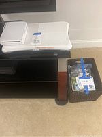 Nintendo Wii console placed on the Wii Balance Board with basket next to it containing controllers and games.