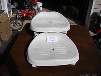 Two white plastic adjustable spa booster seats shown stacked on a table outdoors.