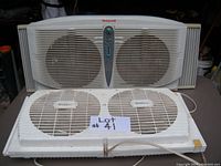 Image of Honeywell dual fan showing two round fans, white color, central control panel, side sealing panels included, dusty condition.