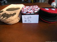 Photo of three pairs of oven mitts on a table with a lot number card visible.