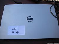 Closed top view of silver Dell laptop with Dell logo in the center.