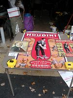 Overview of lot items on table including framed photo and reproduction poster