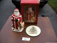 Lenox Santa cookie jar with original box and Spode Christmas Tree hot plate on table outdoors.