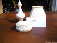 Photo showing all three items: vase, salt shaker, and oval covered container arranged on table with handwritten sign.