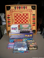 Photo of lot showing wooden checkers/chess board at back with stacked game boxes in front.