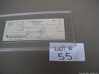 Photo of the front side of the signed check in protective housing, displaying Payee, date, amount, and Lou Costello signature.