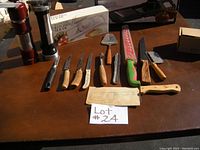 Full view of all kitchen tools included in the lot, showing knives, cutters, mandolins, cookie press, and utensils arranged on the table.