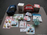 Table view of all miscellaneous lot items including garden figurines, holiday ornaments, pen set, and arm sling