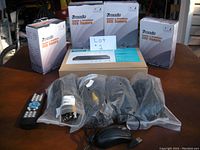 Four boxed Motto CCTV cameras, connection wires, remote control, and 8 channel system box on a table.