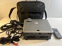 Dell 1800MP projector front and top view with power cable, remote control, and black carrying case.