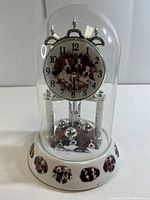 Full view of the glass dome clock showing the porcelain base with dog images and the clock face with dog illustration.