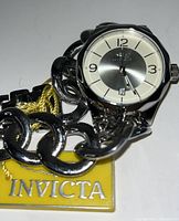 Close-up view of silver dial with Arabic numerals on chain-link stainless steel bracelet, Invicta tag visible.