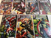 Set of seven Captain America comic books laid flat, showing their cover art with characters and action scenes.