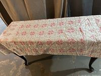 Full view of the vintage quilted tablecloth laid on a wooden table, showing overall pattern and size.