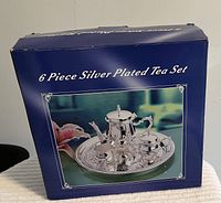 Photo of closed retail box labeled 6 Piece Silver Plated Tea Set with a picture of the set on front.