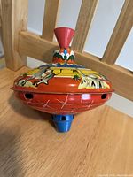 Photo showing top of spinning toy with red handle and colorful western theme paint.