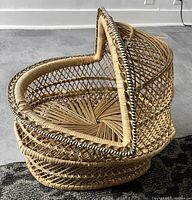 Side view of the wicker doll bassinet showing the curved hood, lattice weave sides, and solid woven bottom.