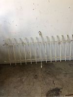 Full view of the antique cast iron gate fence panel showing entire width and height leaning against a wall.