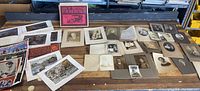 Overview photo of various old photos including black and white portraits, color prints, and movie posters spread on wooden surface