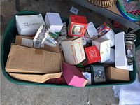 Full view of the large green plastic bin packed with Christmas decoration boxes and loose figurines