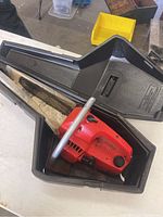 Photo of red Craftsman chainsaw in its black molded carrying case showing the full chainsaw body and part of the case.