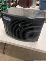 Black commercial chiller with front grill and fan visible, side view.