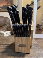 Full view of the wooden knife block containing multiple knives with black handles and stainless steel blades.