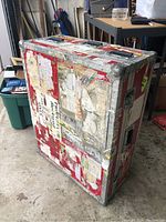 Full view of the large red aluminum case showing worn paper stickers and metal corner protection