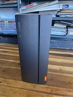 Front view of Lenovo 90GU tower showing brushed black panel with optical drive slot, compact desktop tower design.