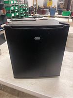 Front view of the black mini fridge showing its compact size and Sunbeam logo on the door.