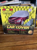 Front view of the Simoniz car cover box showing product image, branding, and features.
