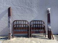 Two sets of headboards, footboards, and wrapped side rails leaning against a wall