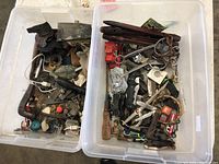 Two large clear plastic boxes filled with assorted vintage metal and collectible items, including spoons, tools, toys, knives, and miscellaneous pieces.
