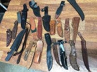 Overview showing entire lot of 20 vintage cutting utensil sheaths placed on wooden table