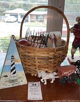 Triangular wooden decor piece painted with Cape Hatteras lighthouse, placed beside the basket and cast iron miniature horse and wagon with Coca-Cola branding.