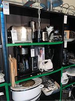 Black adjustable shelving unit with green shelf brackets, showing kitchen appliances placed on shelves.