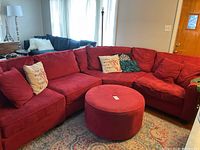 Overview of the entire red sectional sofa and matching ottoman with pillows in living room.
