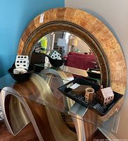 Large round mirror with thick wooden frame and beveled edges reflecting room interior.