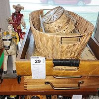 Photo shows three serving trays stacked with two wicker baskets on top, placed on wooden surface by window. Also visible are figurines and wooden horse toy nearby.