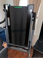 Folded treadmill showing running belt and frame in upright position.